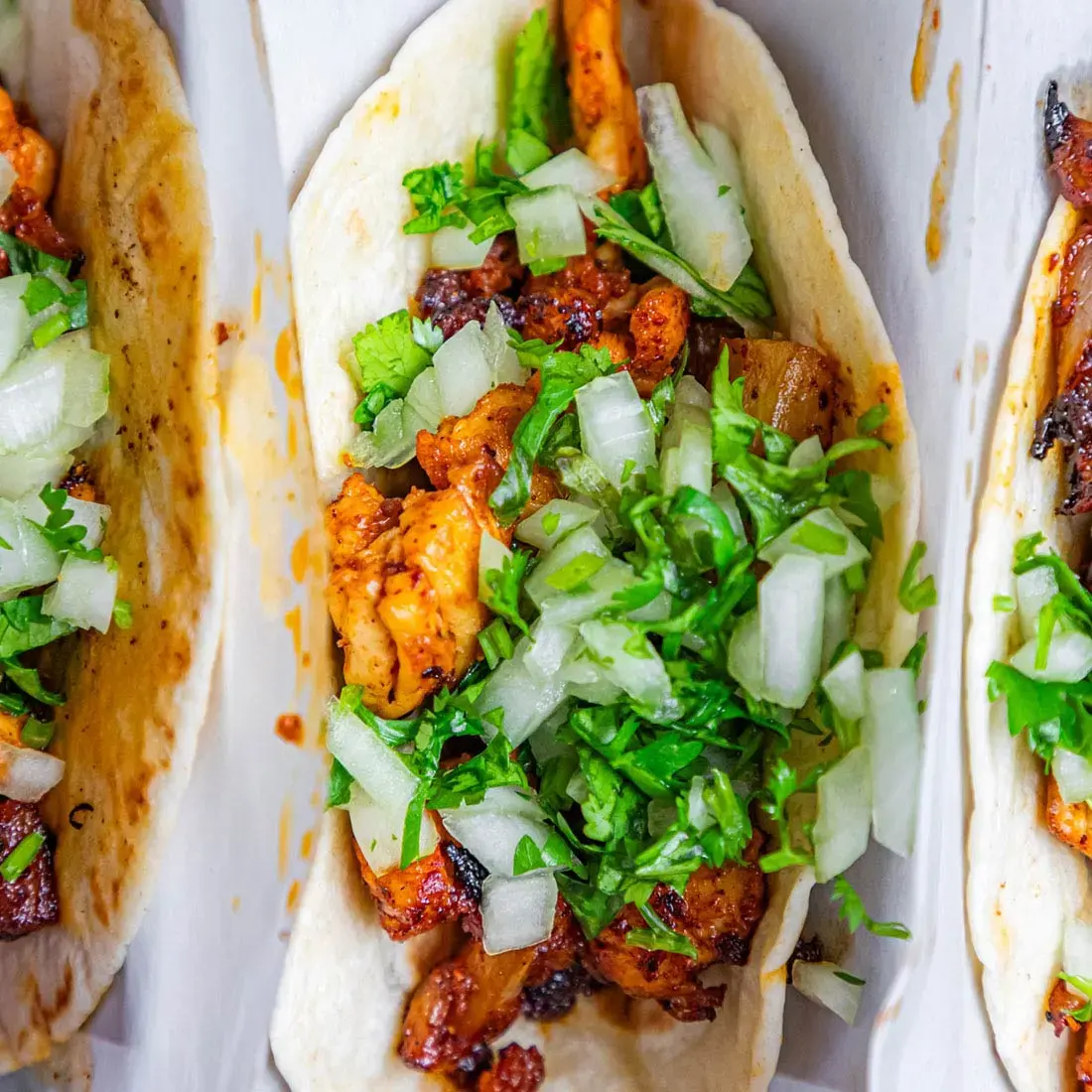 Close-up of tacos topped with grilled chicken, onion and cilantro