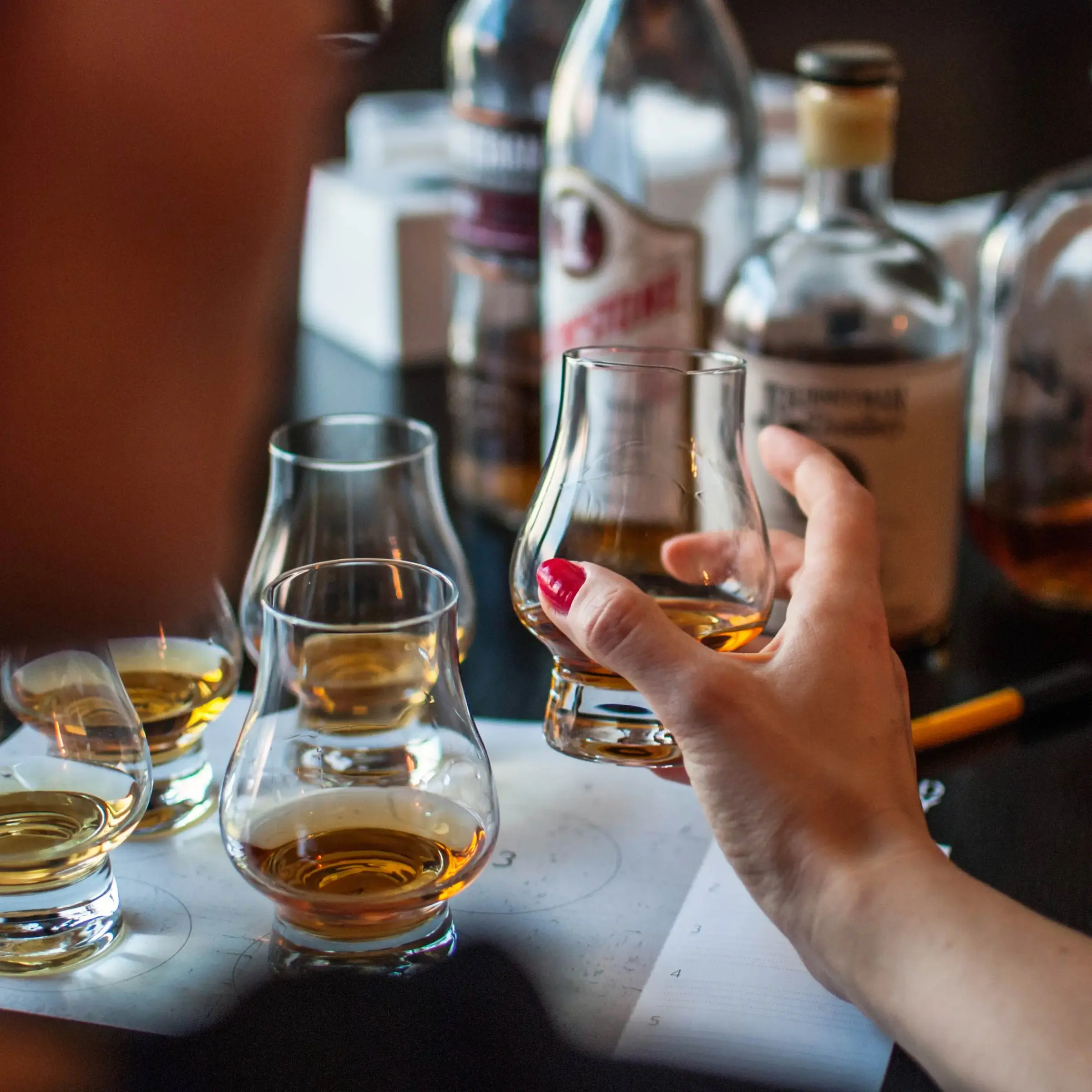 Whiskey tasting glasses being raised at a bar