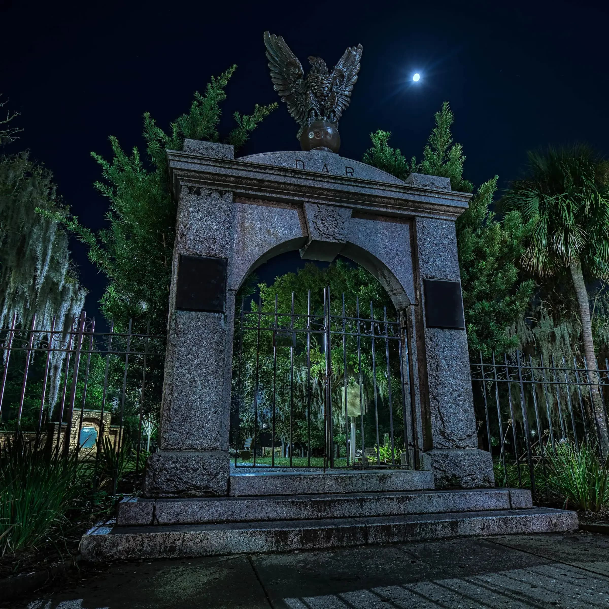 A historic cemetery gate in Savannah lit at night